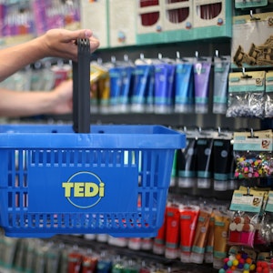Ein Kunde in hält in einer Tedi-Filiale einen Einkaufskorb.