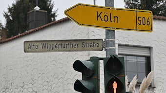 Ein Straßenschild mit der Aufschrift Alte Wipperfürther Straße und ein Wegweiser in Richtung Köln hängen an einem Ampelmast in Bergisch Gladbach.