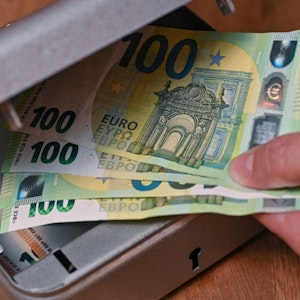 Eine Frau holt Eurobanknoten aus einer kleinen Geldkassette.