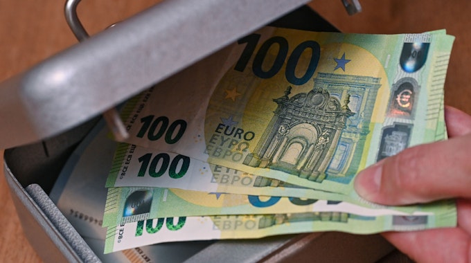 Eine Frau holt Eurobanknoten aus einer kleinen Geldkassette.