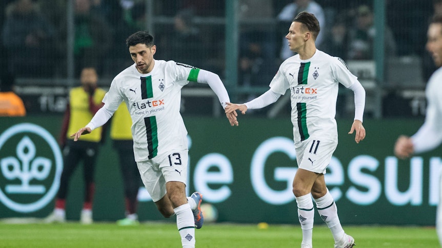 Lars Stindl (l.) und Hannes Wolf klatschen nach dem Treffer von Stindl zum 1:3 im Spiel von Borussia Mönchengladbach gegen Bayer Leverkusen im Laufen ab. Die beiden Gladbach-Spieler tragen das weiße Heimtrikot vom Borussia.