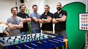 Die fünf Freunde Björn Machel, Viktor Reschetnikow, Marco Ng, Stergios Boucouras und Kevin Latak stecken hinter der Fußballkarten-App. Das Foto zeigt sie vor einem Kicker.