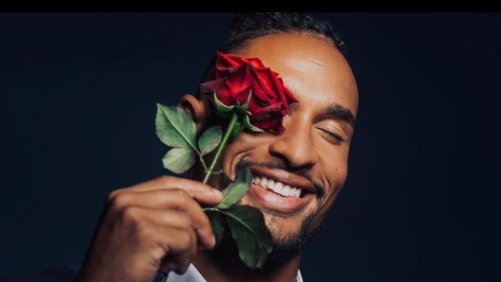 Er ist der neue „Bachelor“: David Jackson geht auf Liebessuche im TV. Er hält sich eine Rose vor sein Auge und trägt ein Anzug.&nbsp;