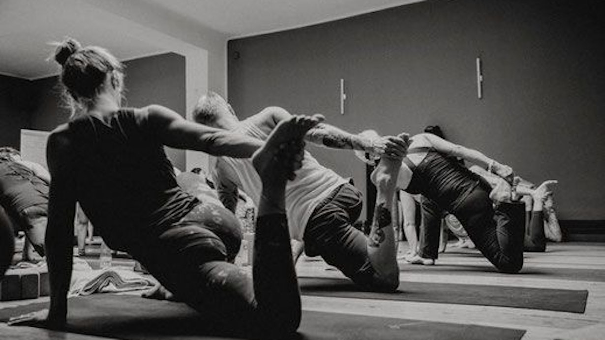 Teilnehmerinnen und Teilnehmer eines Yoga-Kurs in einer Yoga-Position