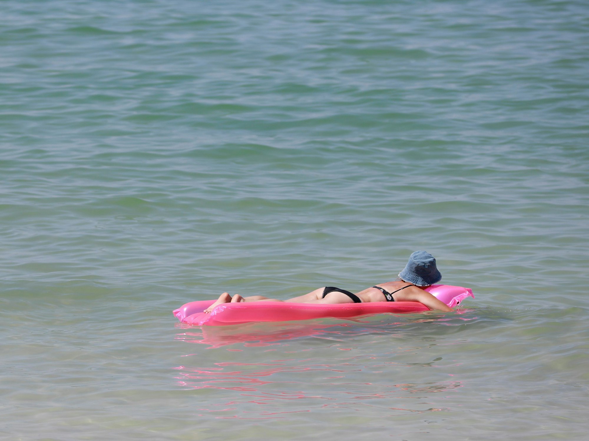 Eine Frau ruht sich im Sommer 2022 in Palma (Mallorca) auf einer Luftmatratze im Meer aus.