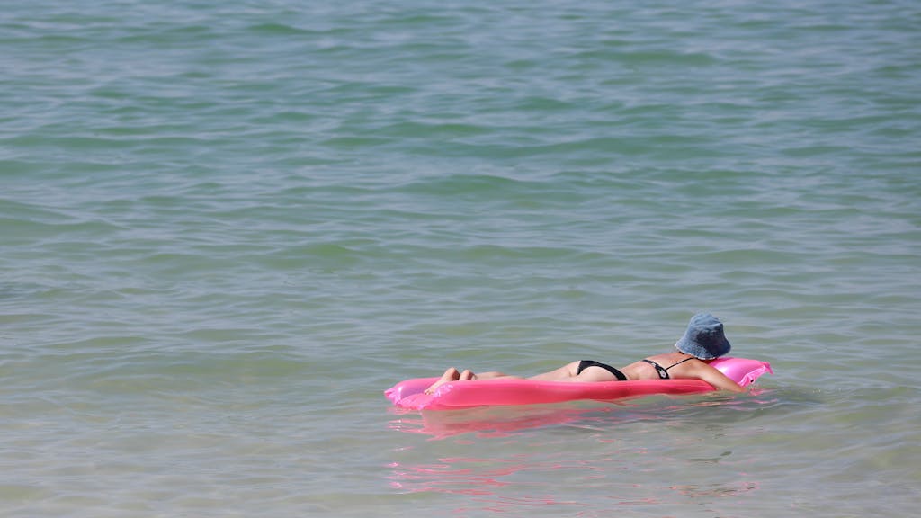 Eine Frau ruht sich im Sommer 2022 in Palma (Mallorca) auf einer Luftmatratze im Meer aus.