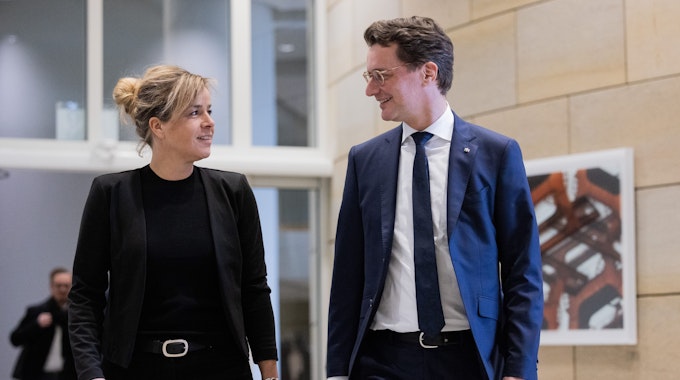 NRW-Ministerpräsident Hendrik Wüst (CDU, r),und seine Stellvertreterin Mona Neubaur (Grüne), Ministerin für Wirtschaft, Industrie, Klimaschutz und Energie sehen einander lächelnd an.