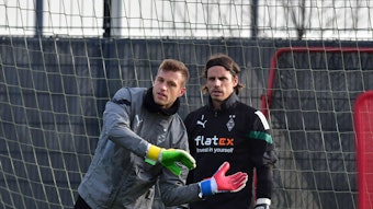 Fabian Otte (l.) macht im Training von Borussia Mönchengladbach eine Übung vor. Yann Sommer steht in Trainingskleidung neben ihm und schaut nach vorne. Otte legt seine Hände vor den Körper von Sommer, beide stehen in einem Tor.
