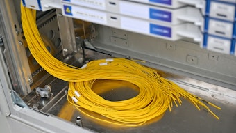 Gelbe Glasfaserkabel liegen in einem Verteilerkasten.