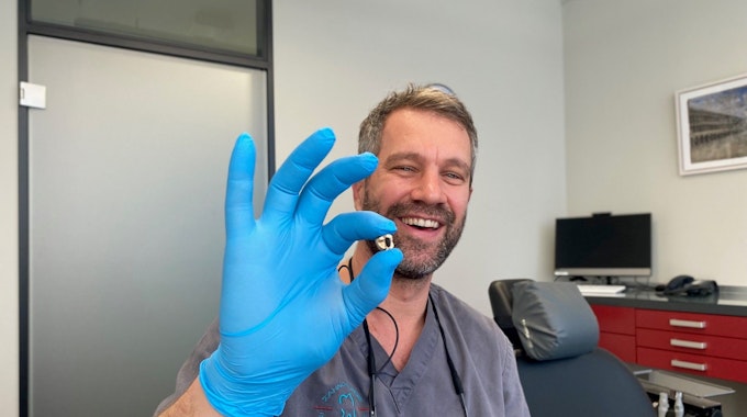 Zahnarzt Benjamin Engelke mit entnommenen Zahngold in der Hand.