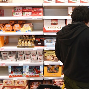 Ein Kunde steht vor einem Süßigkeiten-Regal im Supermarkt.