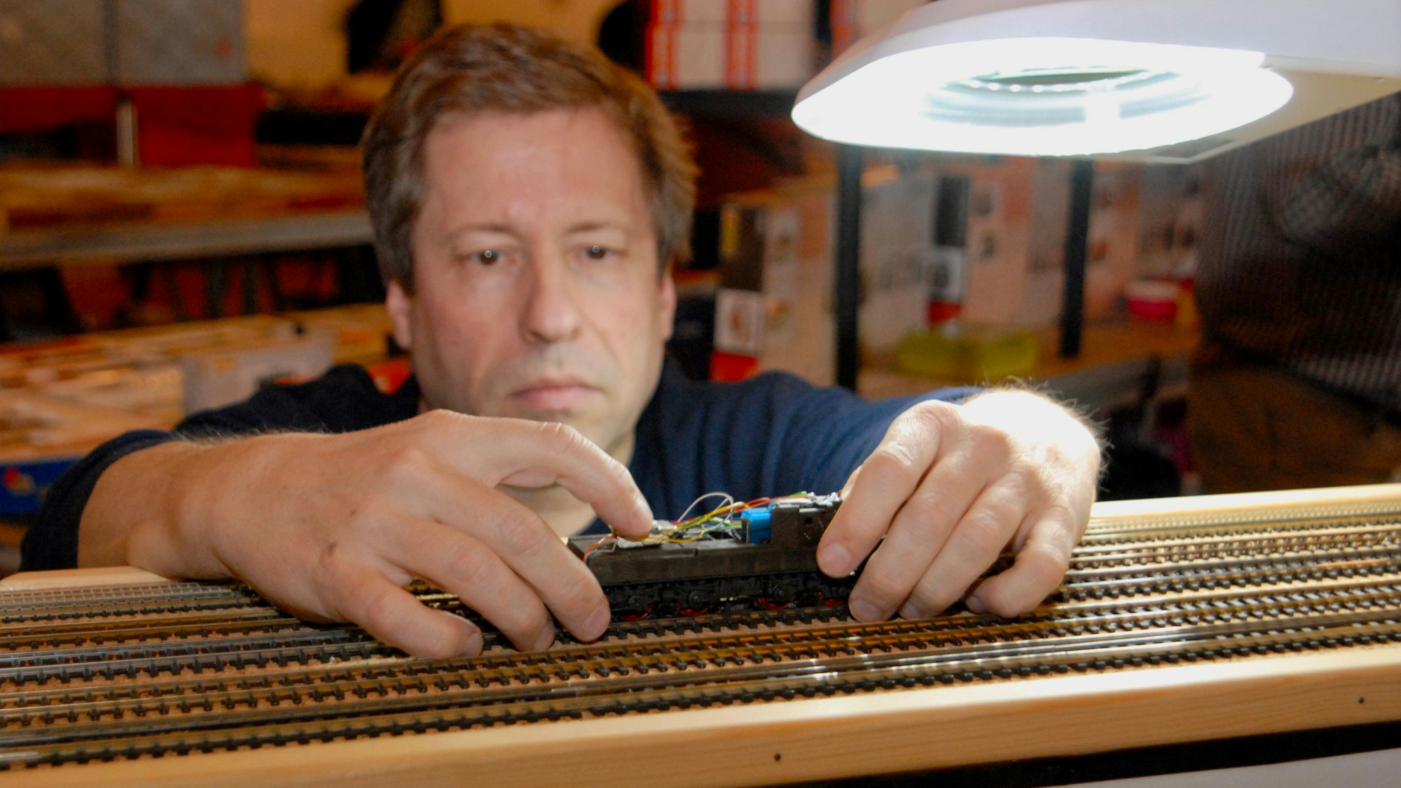 Bahndoktor Dirk Gardemann in seiner Fachwerkstatt mit einer Spielzeugeisenbahn in der Hand.