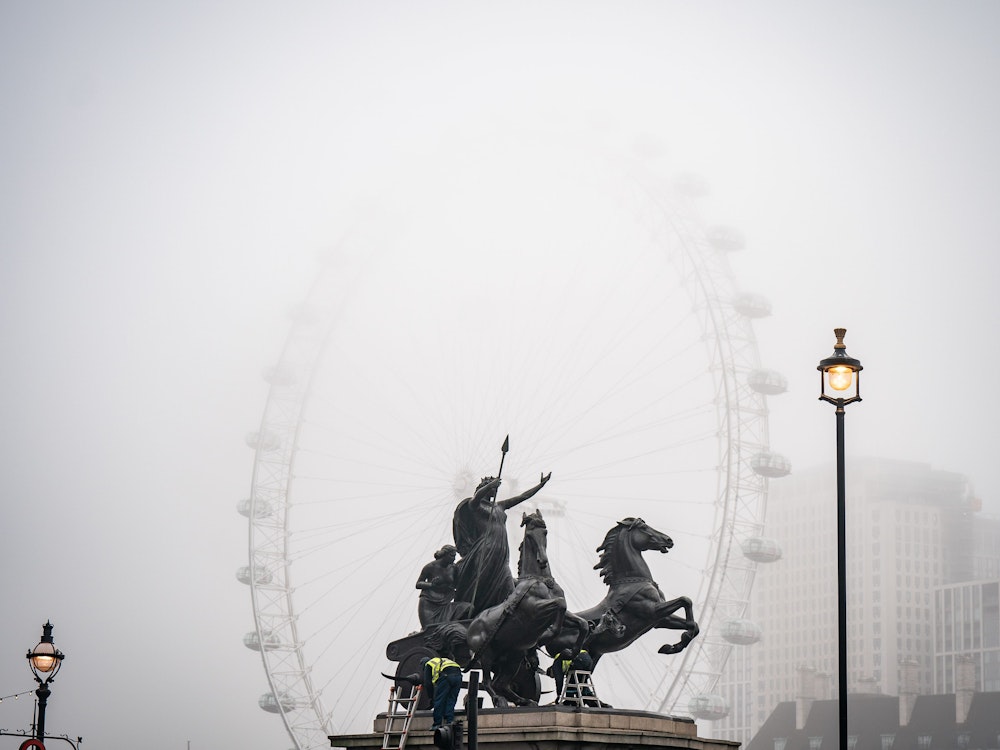 Arbeiter reinigen die Boudiccan Rebellion Statue am Victoria Embankment, während Nebel das „London Eye“ am Südufer der Themse umgibt.