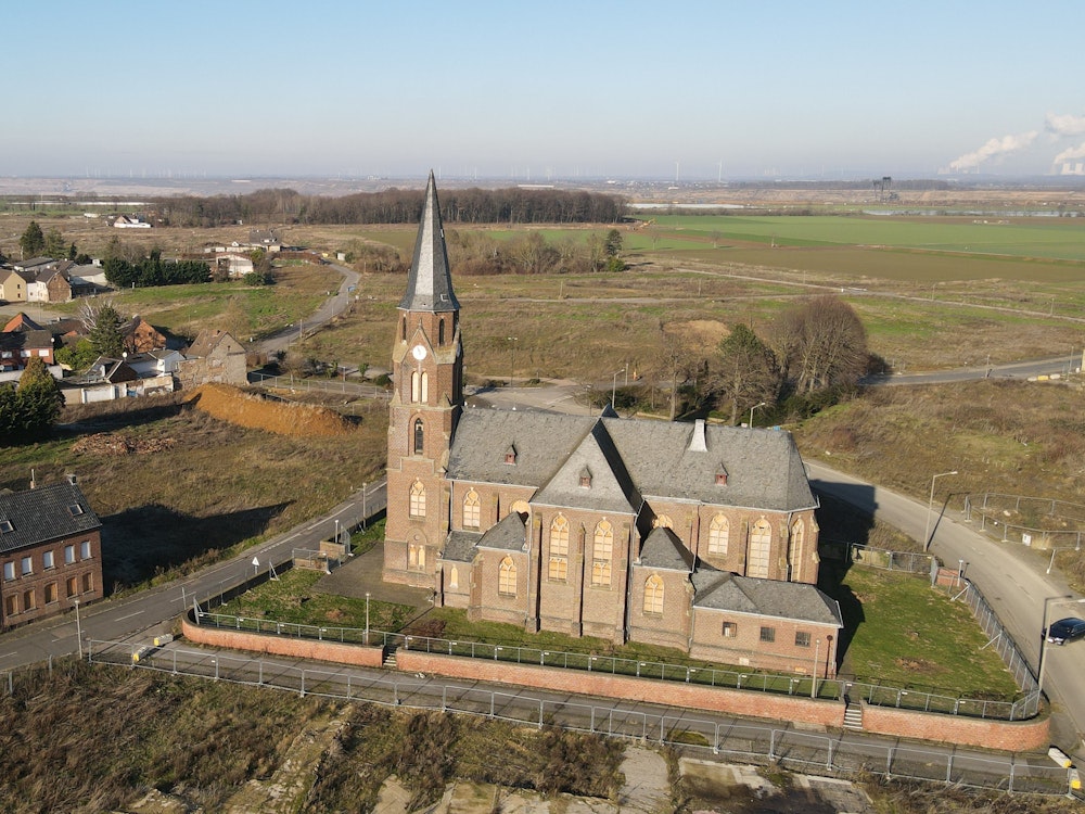 Die Kirche St. Albanus und Leonhardus in Kerpen-Manheim, im Hintergrund befindet sich der Hambacher Tagebau.