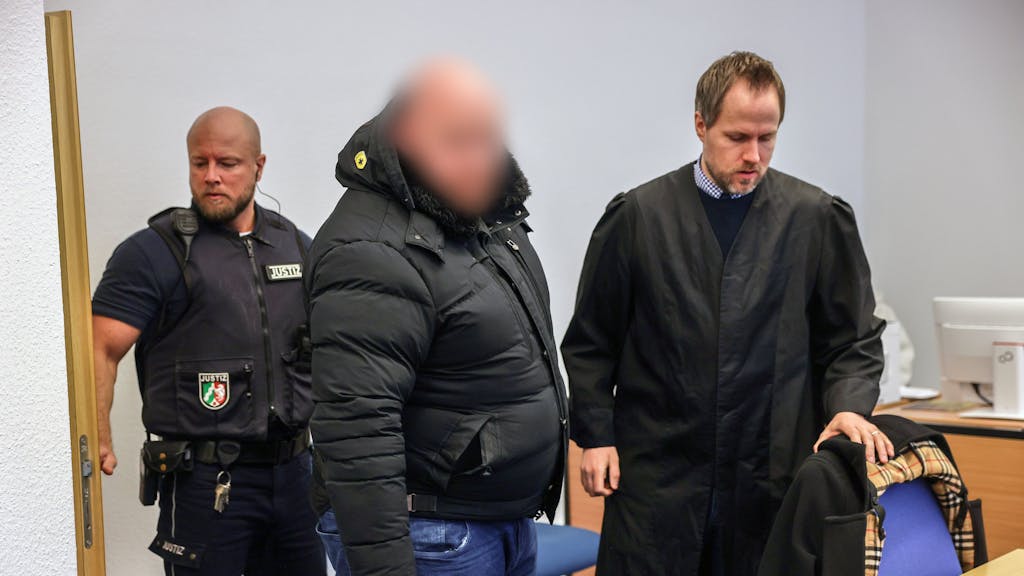 Der Angeklagte (M) steht im Gerichtssaal neben seinem Verteidiger Ingmar Rosentreter (r). Der Mann steh wegen Beteiligung an den Krawallen beim Conference-League-Spiel des 1. FC Köln in Nizza vor Gericht.     