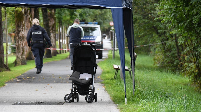 Ein leerer Kinderwagen steht auf einem Weg, abgesperrt mit Flatterband der Polizei.