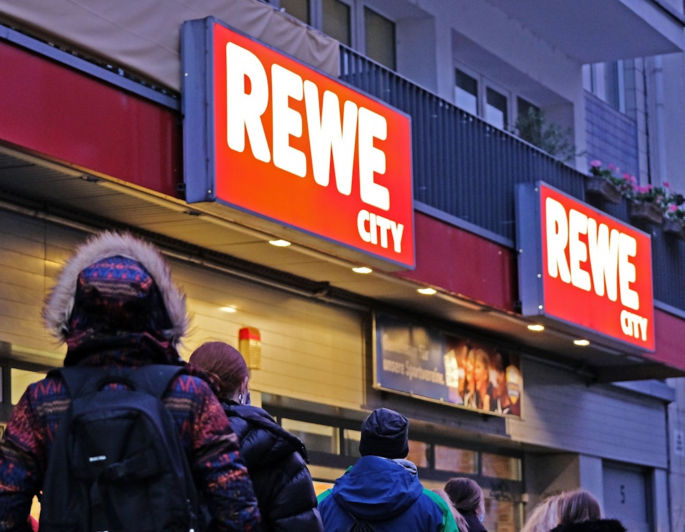 Kundinnen und Kunden vor einem REWE-Supermarkt.