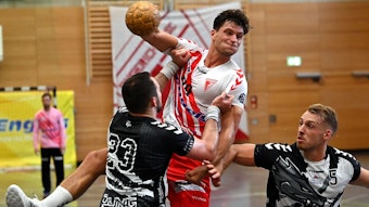 Ein Handballer wird beim Wurfversuch von seinem Gegenspieler am Trikot gehalten.
