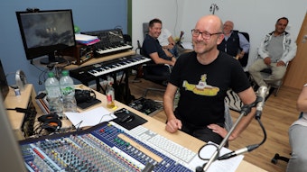 Komponist und Musiker Ralf Hahn sitzt im Tonstudio vor einem Mischpult, dahinter sitzt das Dreigestirn.