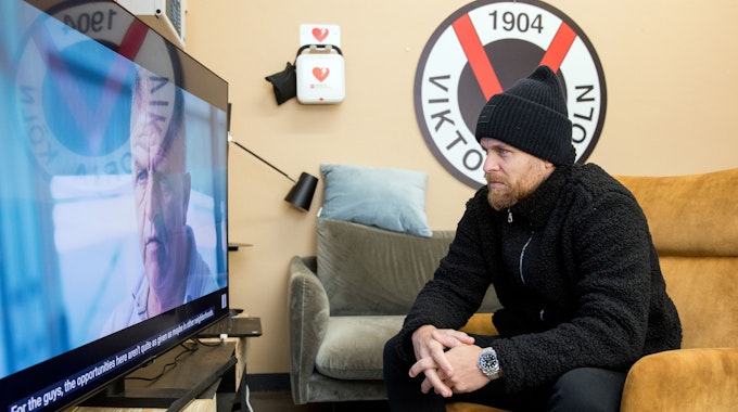 Fußballspieler Mike Wunderlich (Viktoria Köln) sitzt auf dem Sessel und schaut TV.