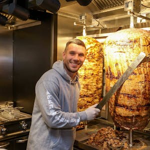 Fußball-Weltmeister Lukas Podolski posiert bei der Eröffnung eines Mangal-Döner-Ladens 2018 an einem Dönerspieß.