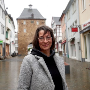 Eine Frau steht auf einer Straße in Bad Münstereifel, im Hintergrund ist das Orchheimer Tor zu sehen.