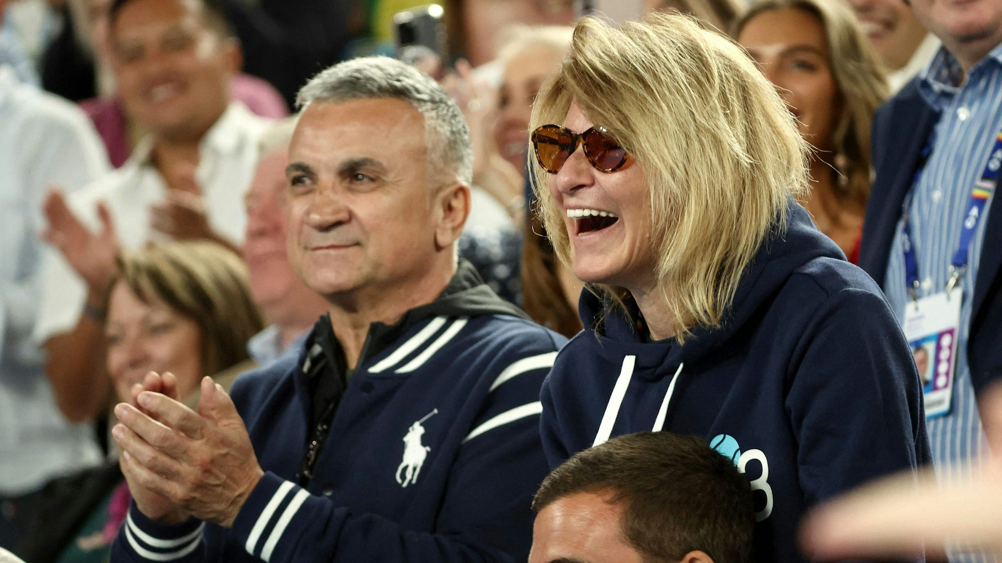 Srdjan Djokovic und Mutter Dijana Djokovic klatschen und lachen beim Spiel ihres Sohnes.