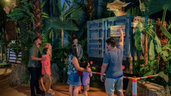 Mehrere Besucher der Jurassic-World-Ausstellung stehen vor einem Modell-Dinosuarier.