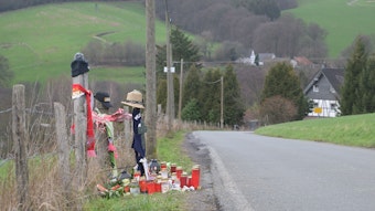Schals, Mützen, Kerzen und Blumen liegen am Straßenrand in Odenthal.