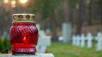 Eine Kerze steht auf einem Grab.