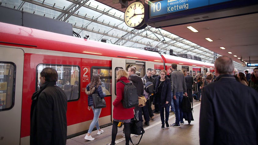 Pendler stehen im Hauptbahnhof Köln vor einer S-Bahn.