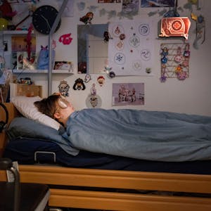 Ed liegt in seinem Bett, er trägt eine Schlafmaske. Vor dem Bett steht ein Rollstuhl. An den Wänden kleben unzählige Bilder, Zeichnungen und Figuren.