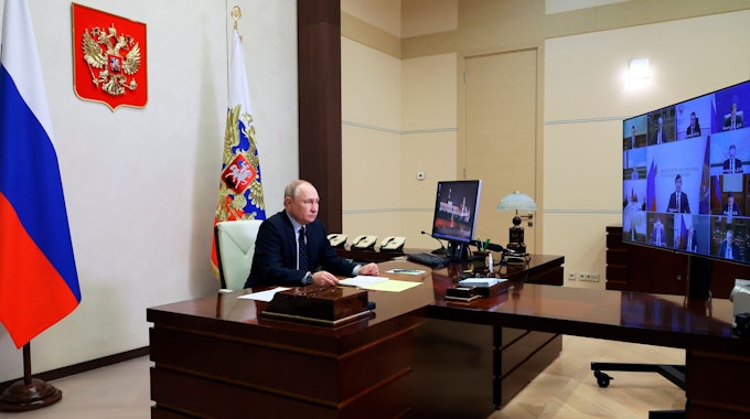 Der russische Präsident Wladimir Putin sitzt während einer Videokonferenz an seinem Schreibtisch.