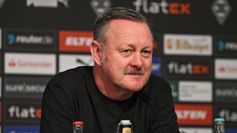 Roland Virkus, Manager von Borussia Mönchengladbach, bei einer Pressekonferenz am 20. Januar 2023 im Borussia-Park. Er schaut verschmitzt und ernst und trägt einen schwarzen Pullover.