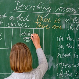 Eine Lehrerin einer Grundschule schreibt in englischer Sprache an die Tafel.