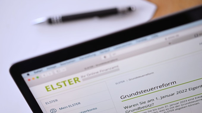 Auf einem geöffneten Laptop-Bildschirm ist eine Seite der „Elster“-Steuerplattform geöffnet, die Informationen über die Grundsteuerreform enthält.