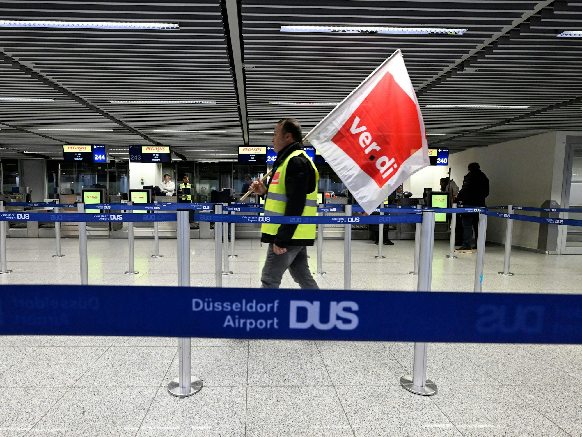 Mann mit Flagge von Verdi spaziert durch den Flughafen in Düsseldorf. Die Gewerkschaft hat zum Streik aufgerufen.