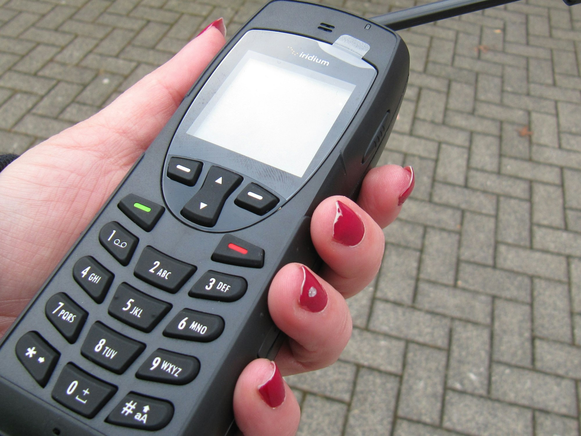 Eine Frauenhand hält ein Satellitentelefon.