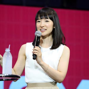 Aufräum-Expertin Marie Kondo 2019 bei einem Vortrag in Japan. Sie trägt ein weißes Oberteil, gestikuliert mit der rechten Hand und hält ein Mikrofon.