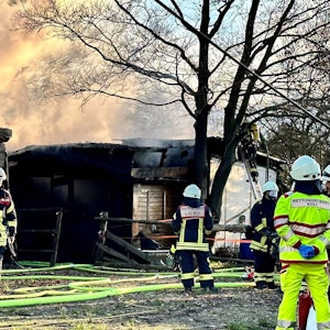 Feuerwehrleute sind bei einem Brand in einer Laube in Köln-Rodenkirchen im Einsatz.