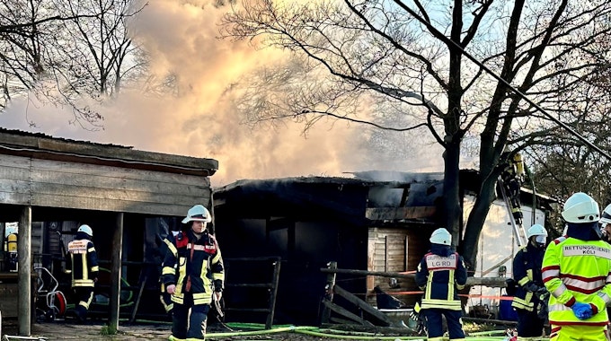 Feuerwehrleute sind bei einem Brand in einer Laube in Köln-Rodenkirchen im Einsatz.