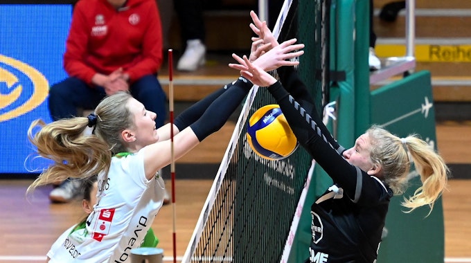 Zwei Volleyballspielerinnen kämpfen am Netz um einen Punkt.