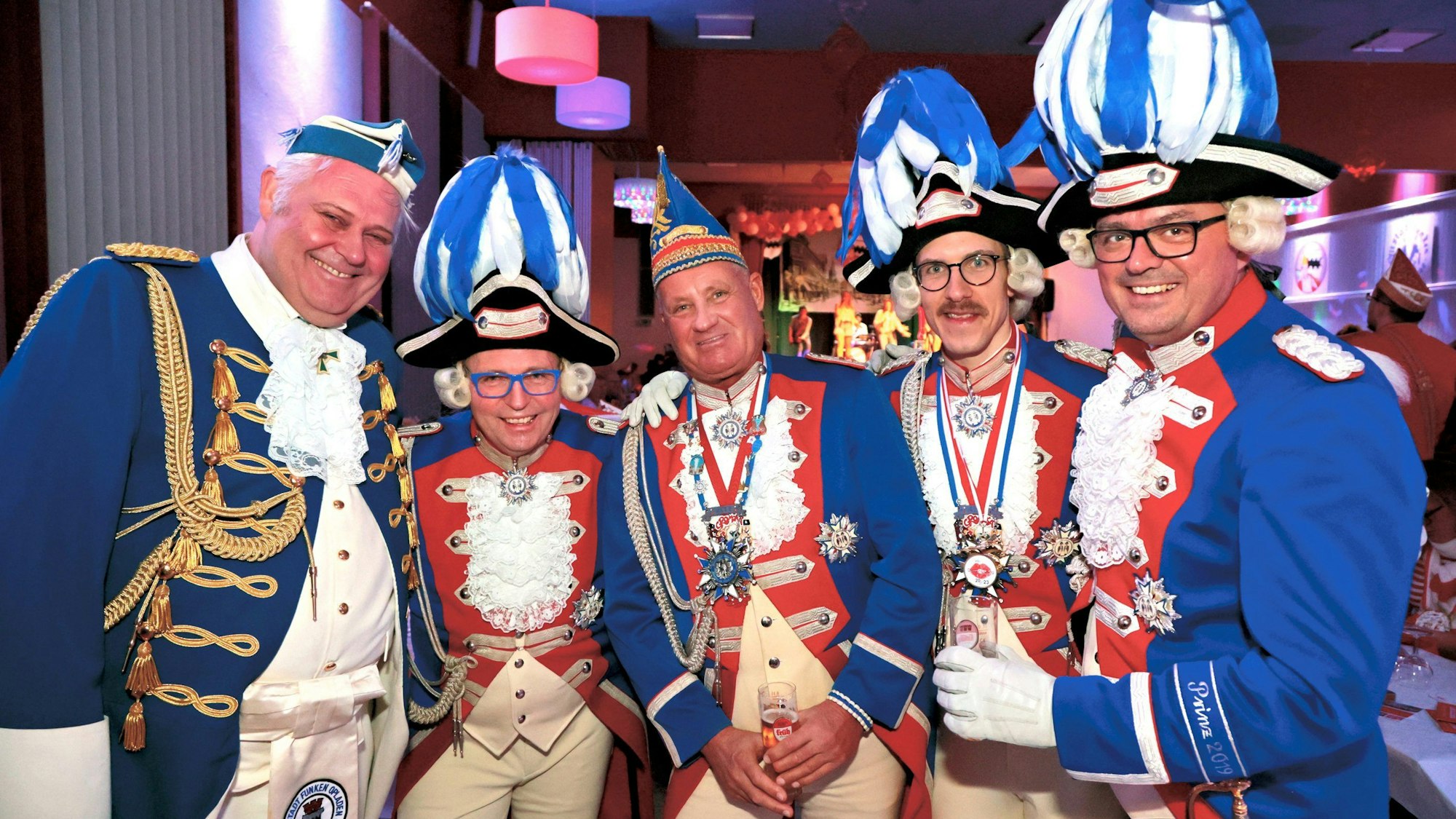 Fünf blau-rot-weiße Funken in Karnevals-Uniformen posieren mit Kölsch-Stangen.