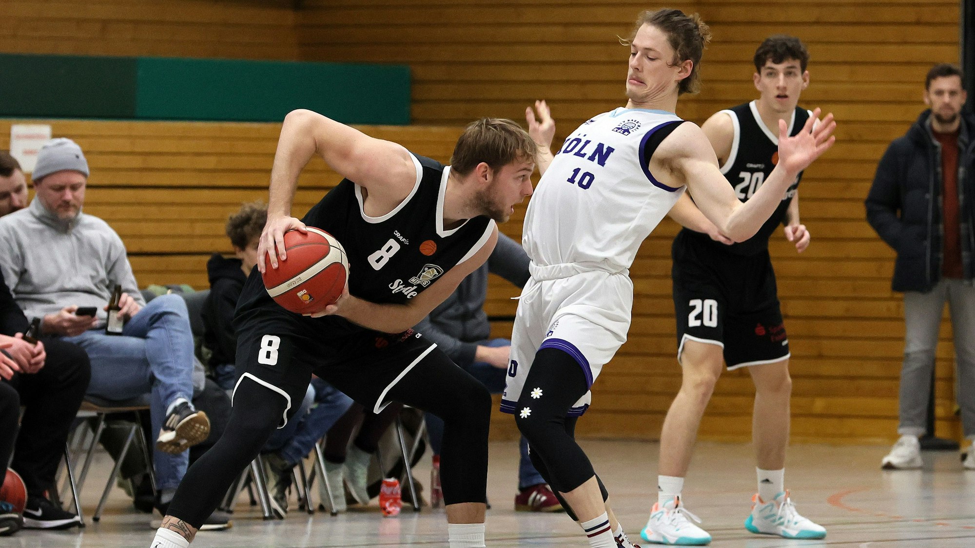 Ein Basketballspieler schützt den Ball vor seinem Gegenspieler.