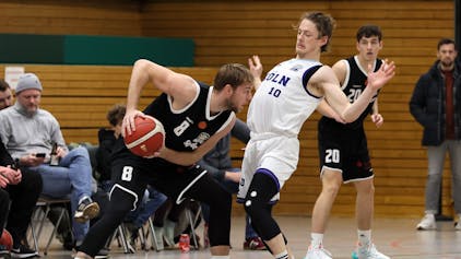 Ein Basketballspieler schützt den Ball vor seinem Gegenspieler.
