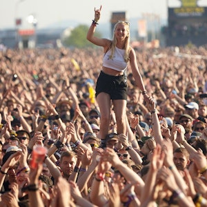 Eine junge Frau steht beim Auftritt der US-amerikanischen Punkband Rise Against vor der Hauptbühne des Musikfestival Rock am Ring auf den Schultern eines Zuschauers.