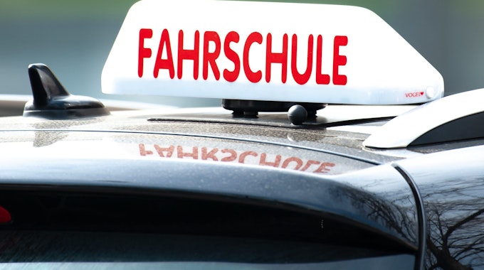 Ein Schild mit der Aufschrift „Fahrschule“ ist auf einem Auto befestigt.