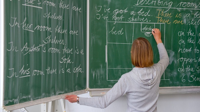 Das Bild zeigt eine Englisch-Lehrerin an der Tafel. In NRW sind mehr als 8000 Stellen von Lehrkräften unbesetzt.