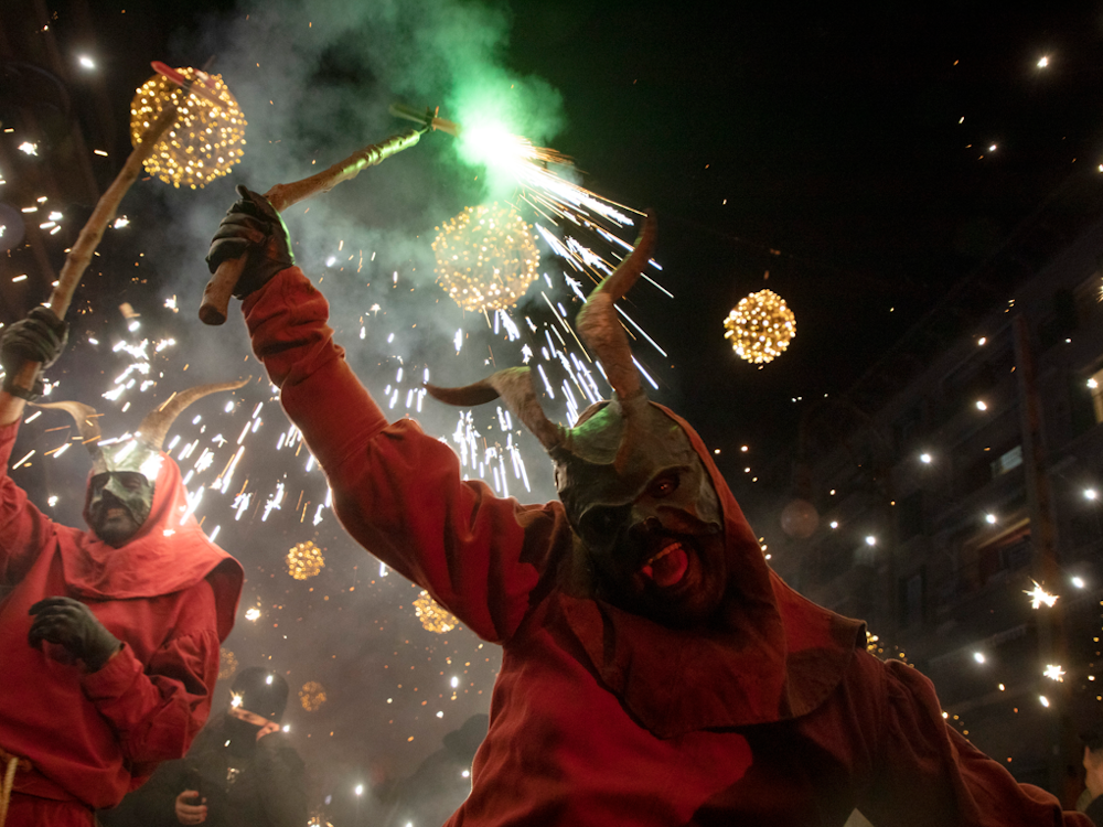 Ein als Dämon verkleideter Mann, der ein Feuerwerk in der Hand hält, läuft während des traditionellen Correfoc zum Abschluss des alljährlichen Stadtfestes zu Ehren des Stadtheiligen Sant Sebastià (Heiliger Sebastian) unter den Menschen.