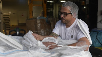 Ein Mann prüft Sojabohnen, die in einem Sack transportiert werden.
